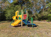 Thumbnail 6 of 29 - Twin Oaks Apartments in Hattiesburg Mississippi photo of a playground with a yellow and green slide and a blue and red slide