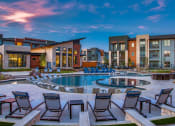 Thumbnail 17 of 18 - Apartments for Rent Grand Prairie - Large Sparkling Pool at Dusk Surrounded by Poolside Lounge Chairs
