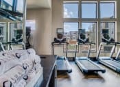 Thumbnail 9 of 18 - Grand Prairie, TX Apartments for Rent - Waters Edge at Mansfield - Athletic Center With Treadmills, Property-Branded Towels, Large Windows, High Ceilings, Large Gym Mirror, and Mounted TV.