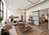 Thumbnail 2 of 25 - A modern living room with a large sofa, a coffee table, and a bedroom in the background.