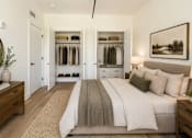 Thumbnail 9 of 25 - A bedroom with a large bed and a wardrobe with clothes hanging on it.