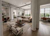 Thumbnail 4 of 25 - A modern living room with a large window and a view of trees outside.