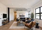 Thumbnail 7 of 25 - A modern living room with a large couch, a coffee table, and a flat-screen TV.