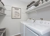 Thumbnail 8 of 19 - Hinton Height_Cottage Grove_MN_a washer and dryer in a white laundry room with a sign that says
