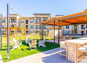 Thumbnail 19 of 29 - A patio with a table and chairs is in front of a building.