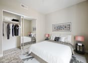 Thumbnail 5 of 18 - One Bedroom Modern Apartments in Long Beach CA - Urban Village - Carpeted Bedroom with a Large Bed, a Large Mirror-Door Closet, Black Nightstands, and Beige Walls