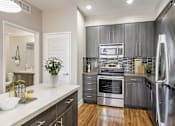 Thumbnail 7 of 18 - A modern kitchen with stainless steel appliances and wooden floors.