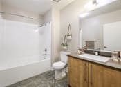 Thumbnail 6 of 18 - A bathroom with a white tub, toilet, and sink.