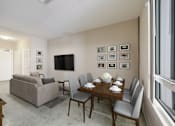 Thumbnail 4 of 18 - A living room with a grey couch, a wooden dining table and grey chairs.