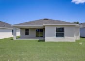 Thumbnail 4 of 29 - Lady Lake, FL Rentals – The Groves at Lake Ella - a grey house with a yard and a blue sky