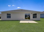 Thumbnail 6 of 29 - Houses in Lady Lake for Rent – The Groves at Lake Ella - a beige house with a yard and a patio