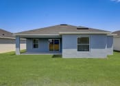 Thumbnail 2 of 29 - Pet-Friendly Rentals in Lady Lake, FL – The Groves at Lake Ella - a blue house with a grass yard and a blue sky
