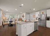 Thumbnail 4 of 30 - a white kitchen with a large island and a stainless steel refrigerator