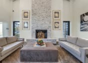 Thumbnail 4 of 40 - Rowlett, TX Apartments for Rent - Village of Rowlett - Interior of High-Ceilinged Community Clubhouse with Wide Couches and Ottoman