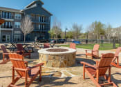 Thumbnail 23 of 40 - an outdoor fire pit with rocking chairs in front of an apartment building