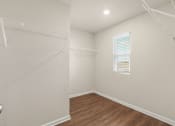 Thumbnail 22 of 30 - a bedroom with a closet and a window and a wooden floor