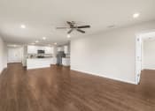 Thumbnail 21 of 30 - a living room with a ceiling fan and a kitchen