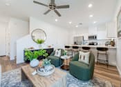 Thumbnail 4 of 20 - Brand-New Townhomes for Rent in Tolleson, AZ - Villas at 91st - Open-Concept Living Room and Kitchen With Ceiling Fan, Recessed Lighting, Armchairs, Coffee Table, and Breakfast Bar Seating.