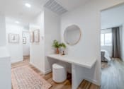 Thumbnail 12 of 20 - A white room with a round mirror and a desk with a plant on it.