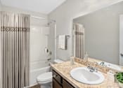 Thumbnail 26 of 63 - A bathroom with a toilet, sink, and shower curtain.