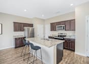 Thumbnail 20 of 63 - A kitchen with a white island and dark brown cabinets.