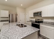 Thumbnail 26 of 38 - A kitchen with granite countertops and stainless steel appliances.