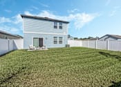 Thumbnail 3 of 63 - A house with a white fence and a green lawn.