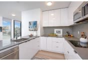 Thumbnail 13 of 54 - Fremont Apartments for Rent - Inspire Fremont - Kitchen with Stainless Steel Appliances, Granite Countertops, White Cabinets, and Hardwood Style Flooring