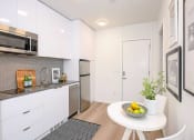 Thumbnail 2 of 54 - Apartments in Seattle, WA for Rent - Inspire Fremont - Kitchen with a Dining Area, White Modern Cabinets, and Stainless-Steel Appliances