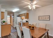 Thumbnail 20 of 47 - Spokane, WA, Pet-Friendly Apartments - Canyon Bluffs - Dining Area Beside Galley Kitchen With Wood-Style Flooring, Ceiling Fan Lighting, White Appliances, And Warm Wood Cabinets.