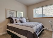 Thumbnail 27 of 47 - Dog-Friendly Apartments in Spokane, WA - Canyon Bluffs - Bedroom With Neutral Walls, Plush Carpet, Large Window With Blinds, Styled Bed, And Compact Desk Area.