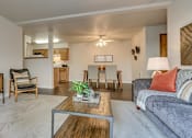 Thumbnail 28 of 47 - Pet-Friendly Apartments in Spokane, WA - Canyon Bluffs - Open Living Room With Plush Carpet, Wood-Style Flooring, Dining Area, Ceiling Fan, And Connected Kitchen.