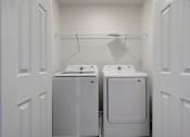 Thumbnail 36 of 36 - Two white front load washing machines in a small laundry room.