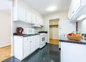 Thumbnail 47 of 66 - A kitchen with white cabinets and black countertops.