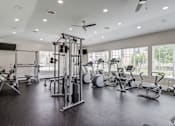 Thumbnail 25 of 33 - a gym with cardio machines and weights in a building with large windows