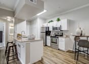 Thumbnail 1 of 33 - a kitchen with white cabinets and stainless steel appliances and a bar with stools
