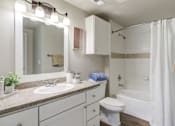 Thumbnail 9 of 33 - a bathroom with wood floor and white cabinets and bathtub and mirror and lights