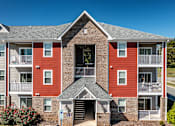 Thumbnail 9 of 21 - Exterior of Hawks Landing Apartments in Hickory, NC with red and gray building and clear blue sky