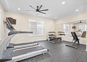 Thumbnail 17 of 21 - Spacious fitness center at Hawks Landing Apartments in Hickory, NC with treadmills, ellipticals, and ceiling fan