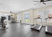 Thumbnail 3 of 21 - A spacious gym with treadmills, elliptical machines, and a ceiling fan.