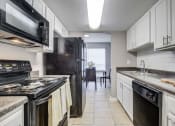 Thumbnail 1 of 29 - Westchase Apartments in Harvey LA photo of a kitchen with white cabinets and black appliances and a black refrigerator