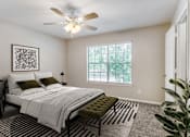 Thumbnail 12 of 39 - A bedroom with a bed, a bench, and a ceiling fan.