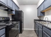 Thumbnail 18 of 33 - Whitney Manor Apartments in Gretna, LA photo of kitchen with black granite and blue cabinets
