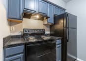Thumbnail 17 of 33 - Whitney Manor Apartments in Gretna, LA photo of  a kitchen with black appliances and blue cabinets