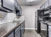 Thumbnail 9 of 33 - Whitney Manor Apartments in Gretna, LA photo of kitchen with subway tile back splash and hardwood floors