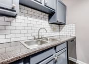Thumbnail 10 of 33 - Whitney Manor Apartments in Gretna, LA photo of  a kitchen with a sink and white subway tiles