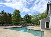 Thumbnail 17 of 25 - A pool surrounded by trees and chairs.