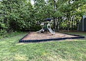 Thumbnail 14 of 25 - A playground with a slide and a swing set in a grassy area.