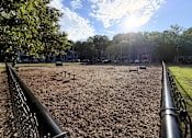 Thumbnail 16 of 25 - A playground with a metal fence and a dirt ground.