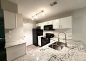 Thumbnail 2 of 25 - A kitchen with granite countertops and white cabinets.